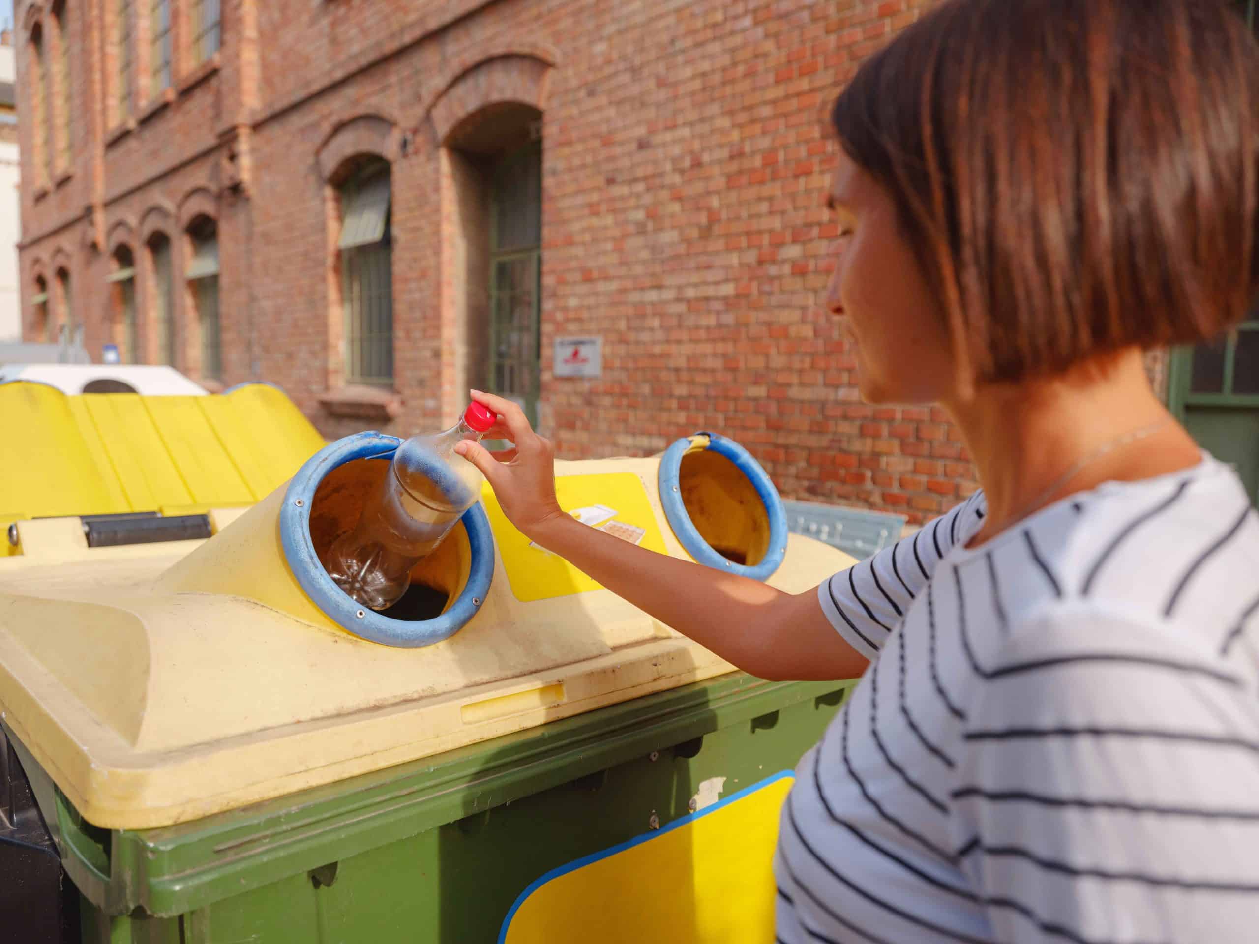 woman throwing plastic bottle Recycling bin stand on european street. Waste separation rubbish before drop to garbage bin to save world, environment care. Pollution trash recycling management concept