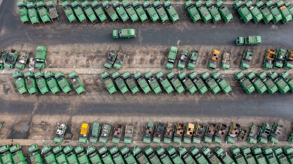 Aerial view of green garbage trucks parking, Many dumpsters and garbage trucks sorting and recycling