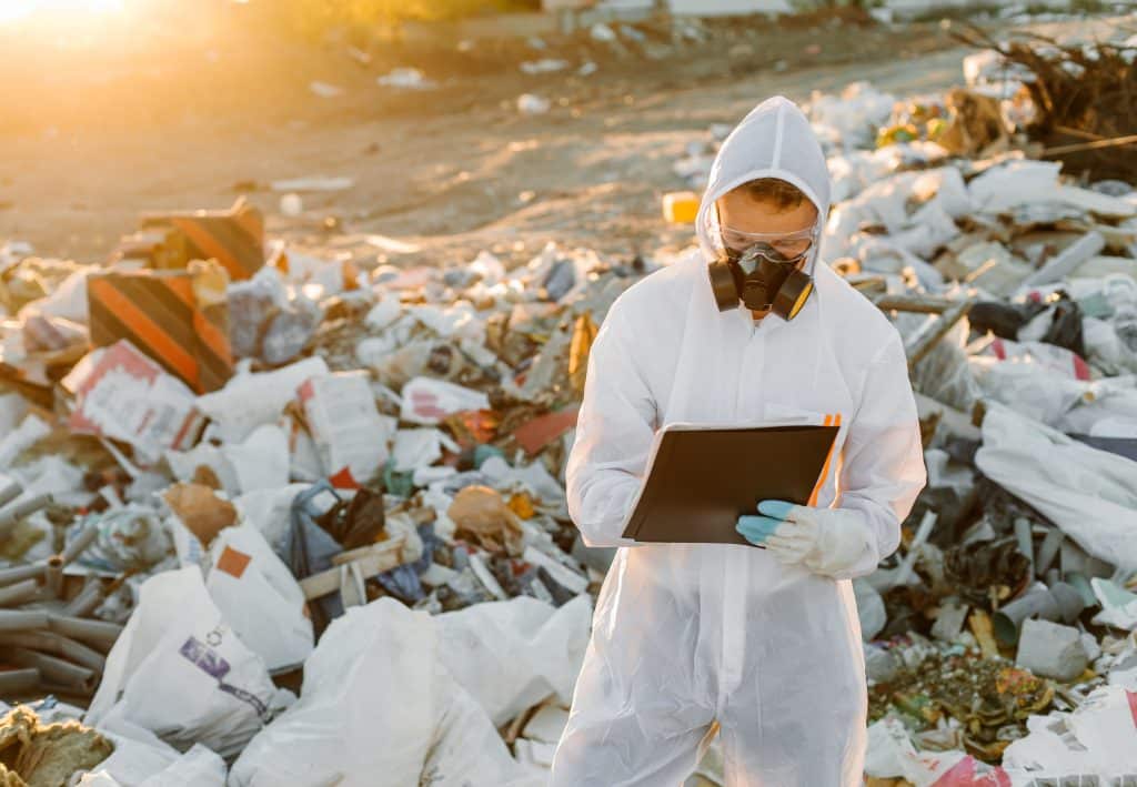 Researcher looking at plastic landfill analyzing environmental pollution level
