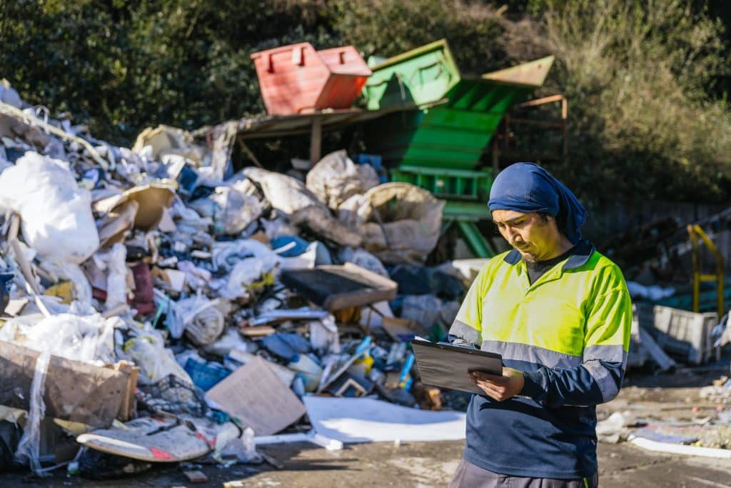 Worker Inspecting Recycling Pile in Recycling Center
