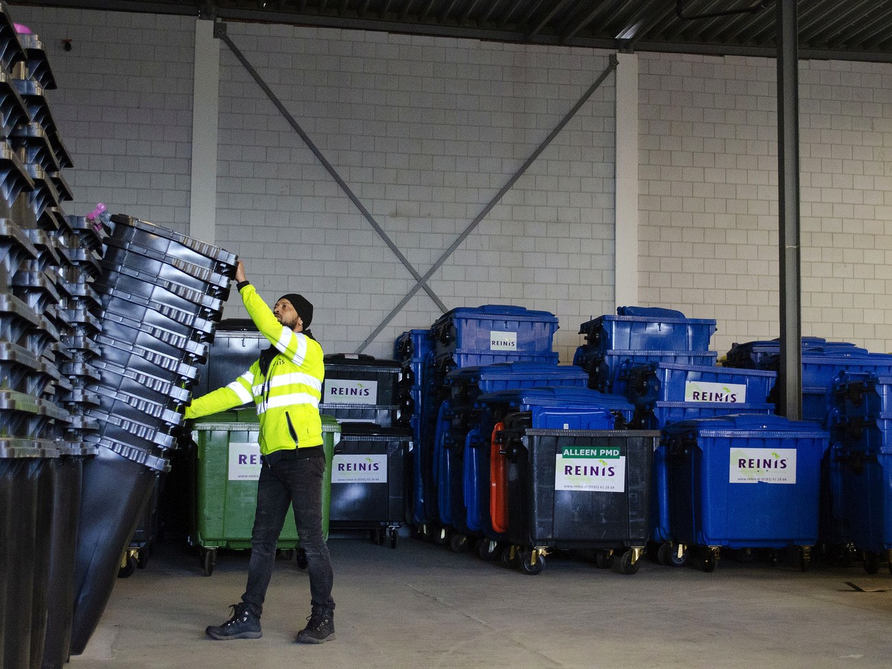 Warehouse worker sorting and stacking commercial waste containers ready for subcontractor collection