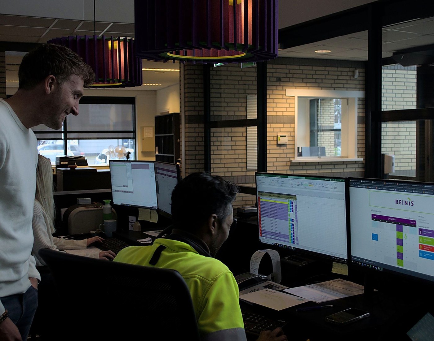 Operations team reviewing client accounts and service schedules on office monitors