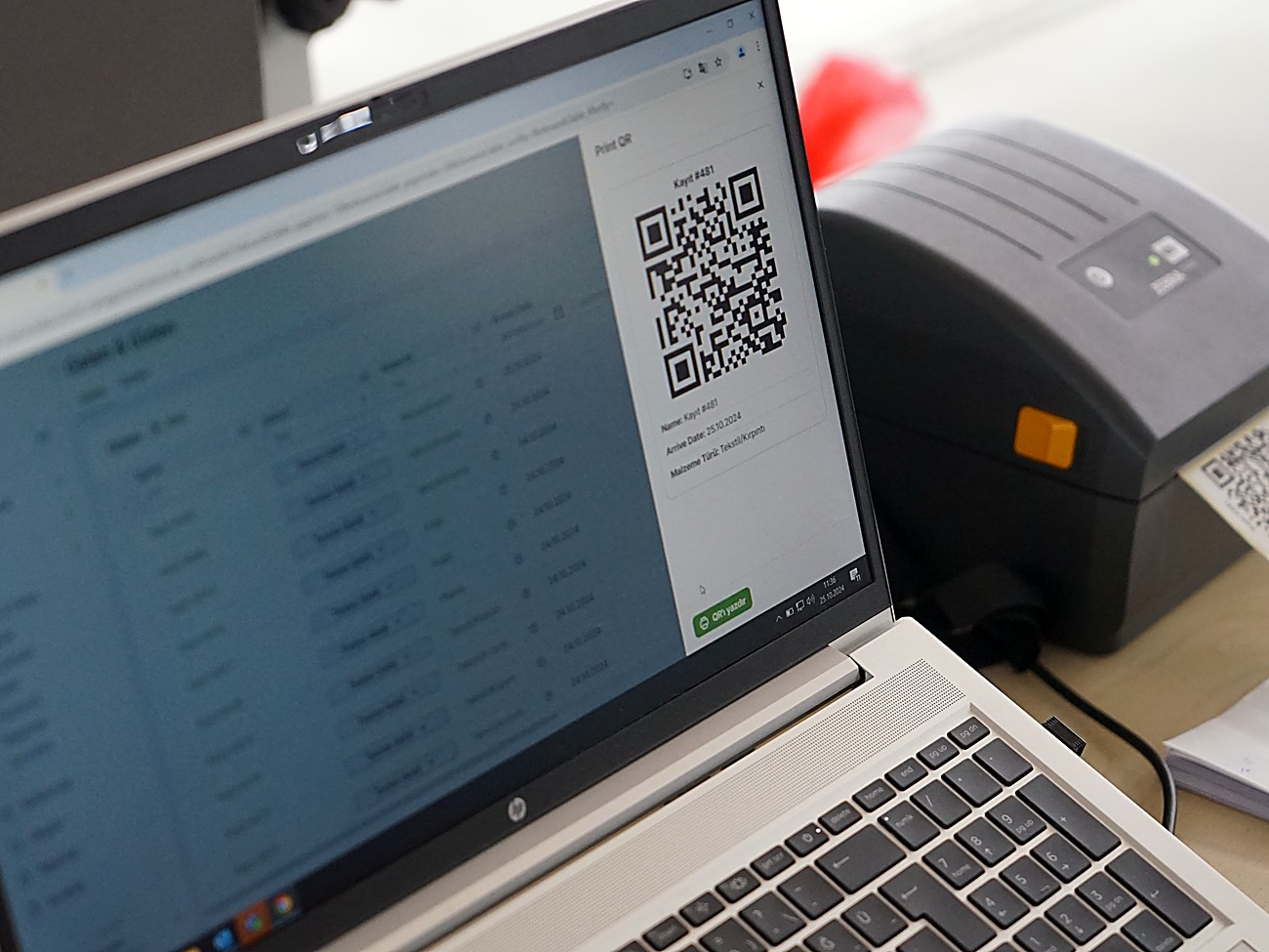 Laptop running WasteDashboard generating a QR code next to a label printer, tagging a waste batch for traceability