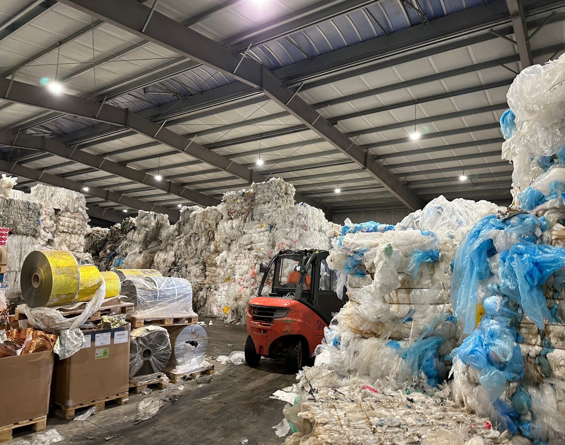 Baled recyclable material staged in a materials recovery facility, with a forklift moving bales