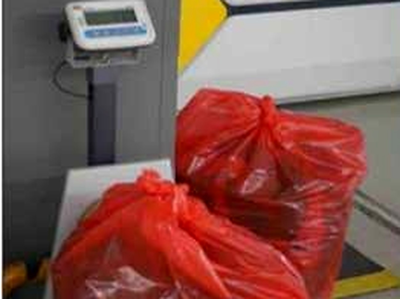 Facility worker weighing sealed waste bags on a digital scale as part of WasteDashboard batch-level tracking