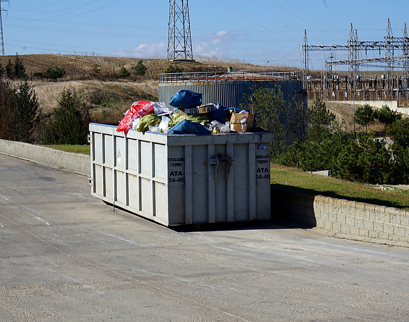 A waste container overflowing with bags and boxes at an industrial site, the kind of issue Evreka AI Camera flags automatically